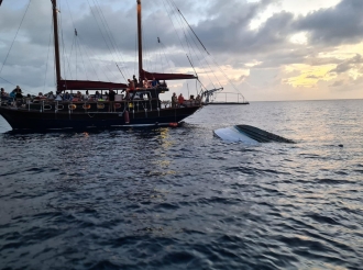 Turistanan mirando un boto cu a kapseis na Bonaire